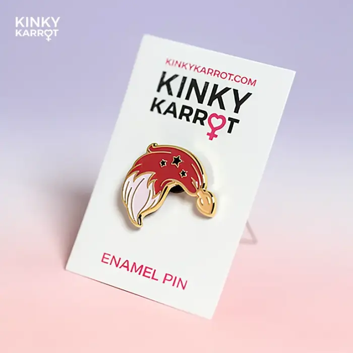 Red fox tail butt plug enamel pin with gold stars on a pink gradient background