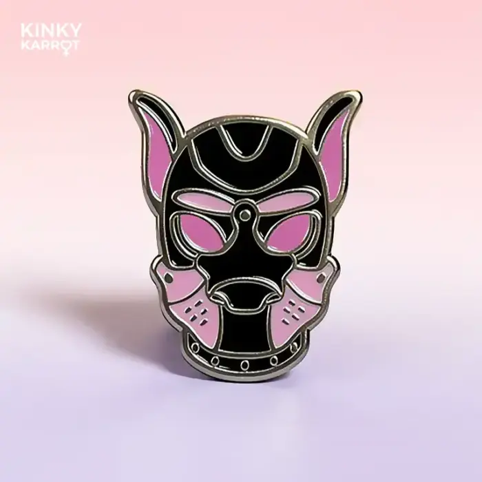 close-up of pink puppy play mask enamel pin on pastel background