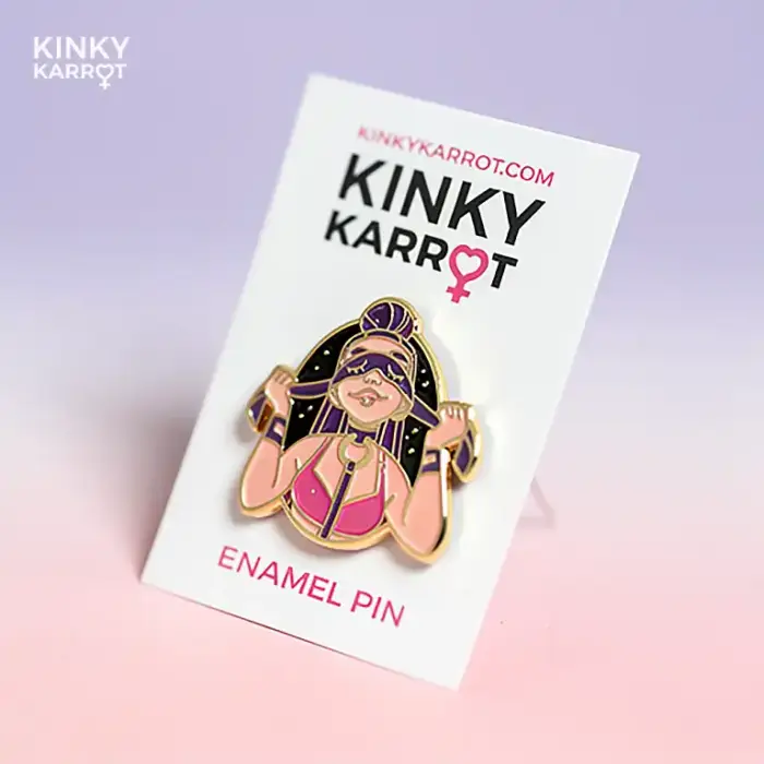blindfold enamel pin with femme figure in pink harness smiling with mask