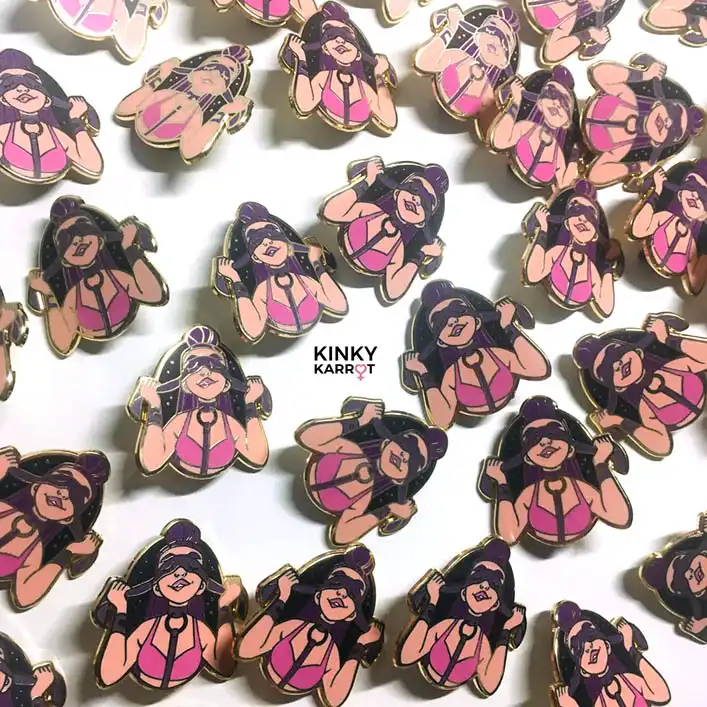 blindfold enamel pin with femme figure in pink harness smiling with mask